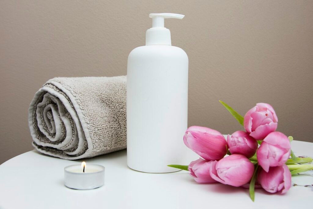 Serviette grise, flacon et fleurs roses dans une ambiance de bien-être